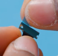 Photo that shows a finger holding a small camera connector tab during removal.