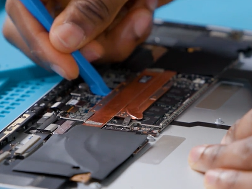 Photo that shows using a plastic opening tool to separate the thermal module from the motherboard.